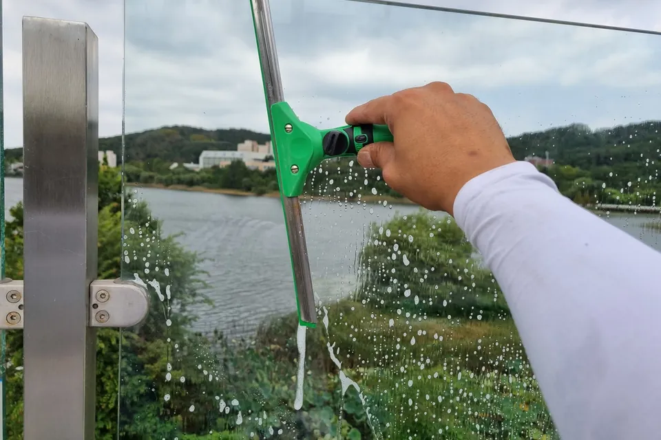 외부 유리면을 도구로 세척하며 접근 조건을 확인하는 모습